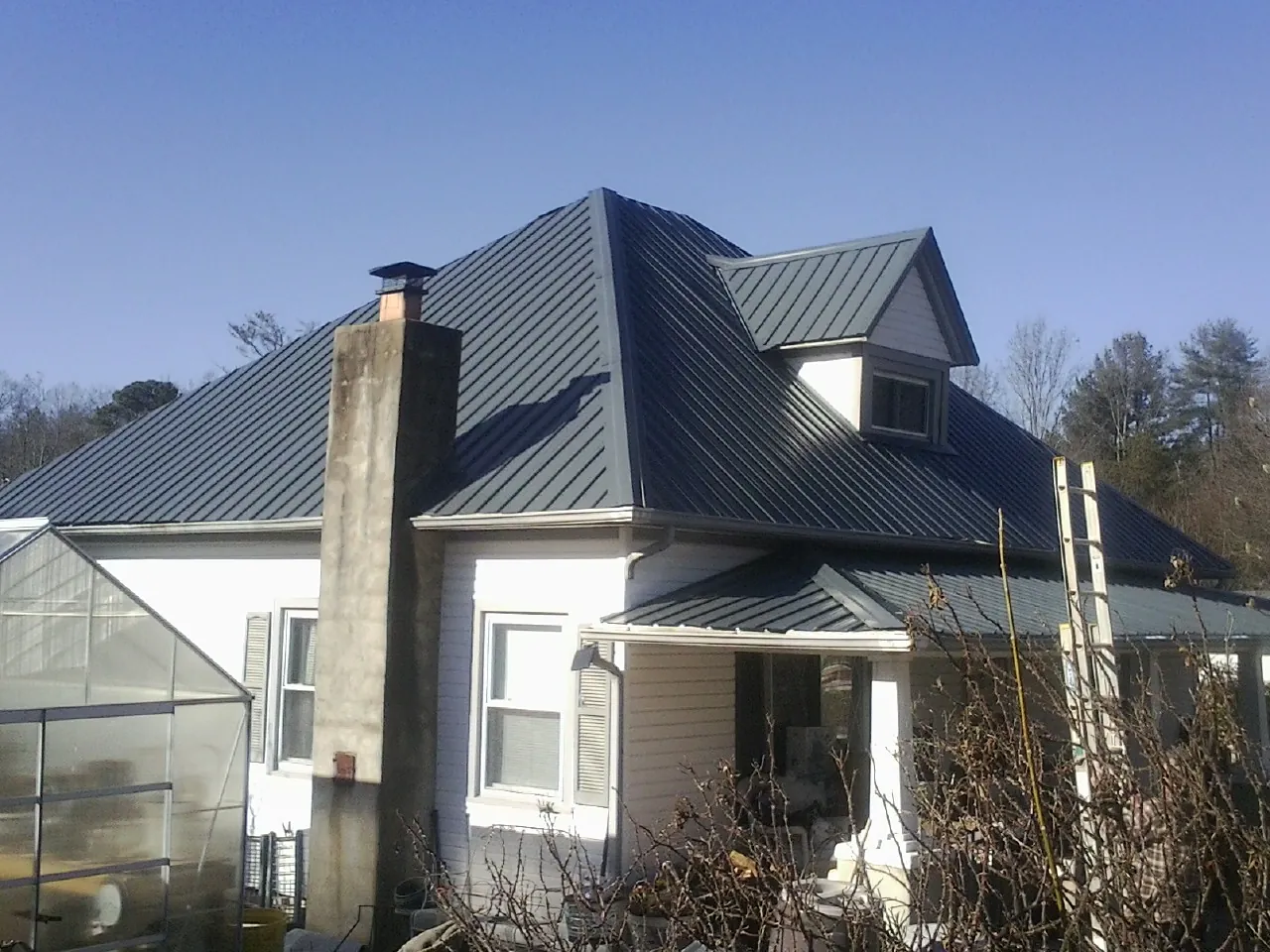 Dark blue standing seam metal roof on a white farmhouse with dormer — Slate & Tile Roof Repair by Roofing Brothers in Montana Mines