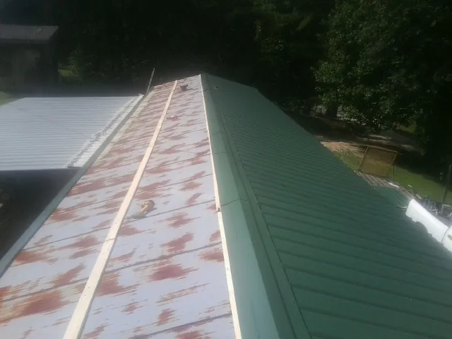 Old rusted panels beside newly installed green metal roofing — Wind Damage Roof Repair by Roofing Brothers in Montana Mines