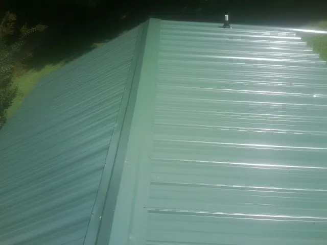 New green metal panels meeting at the ridge of a roof — Flat Roof Repair work by our crew in Montana Mines