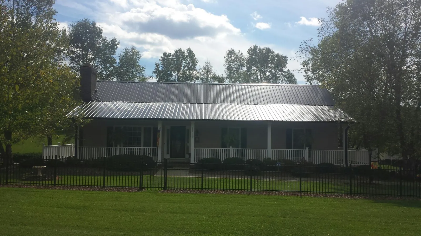 Gray metal roof on a brick ranch with a full width front porch — Gutter Guard Installation work by our crew in Montana Mines