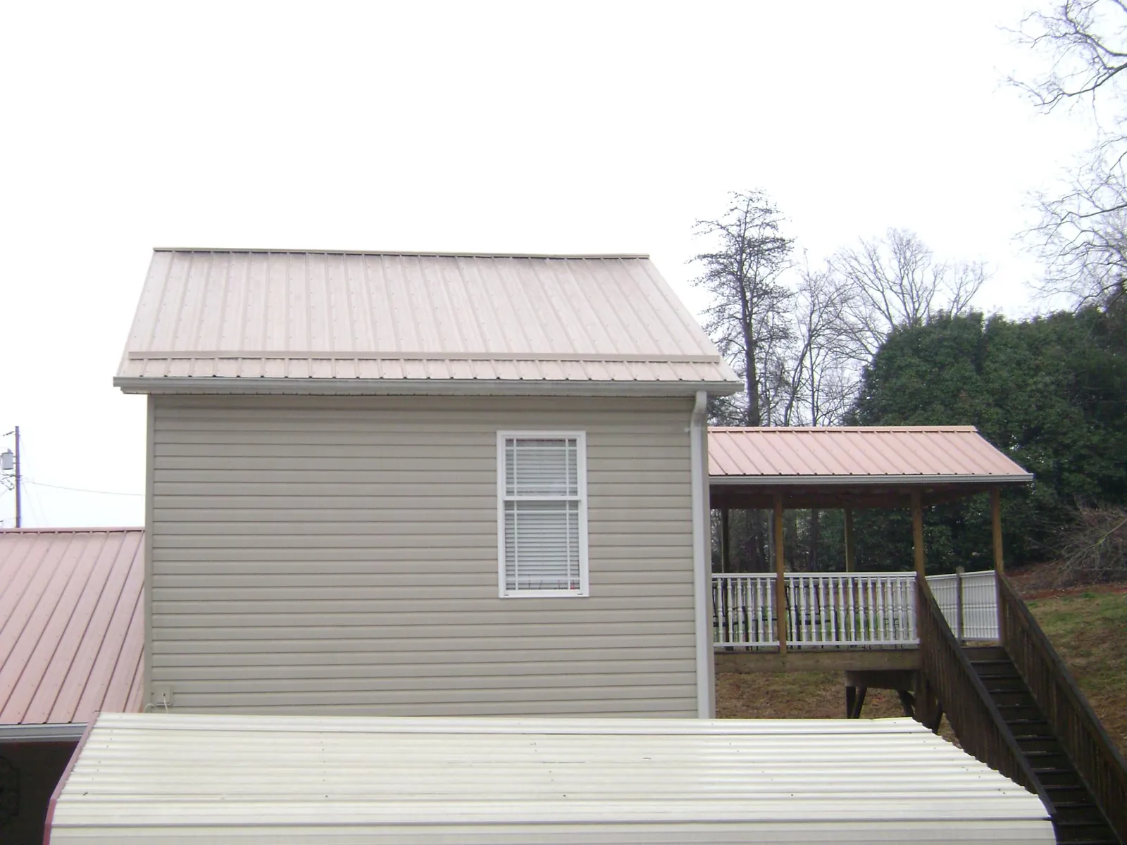 Tan metal roofs on a two story addition and attached porch, from a Roof Replacement job in Montana Mines