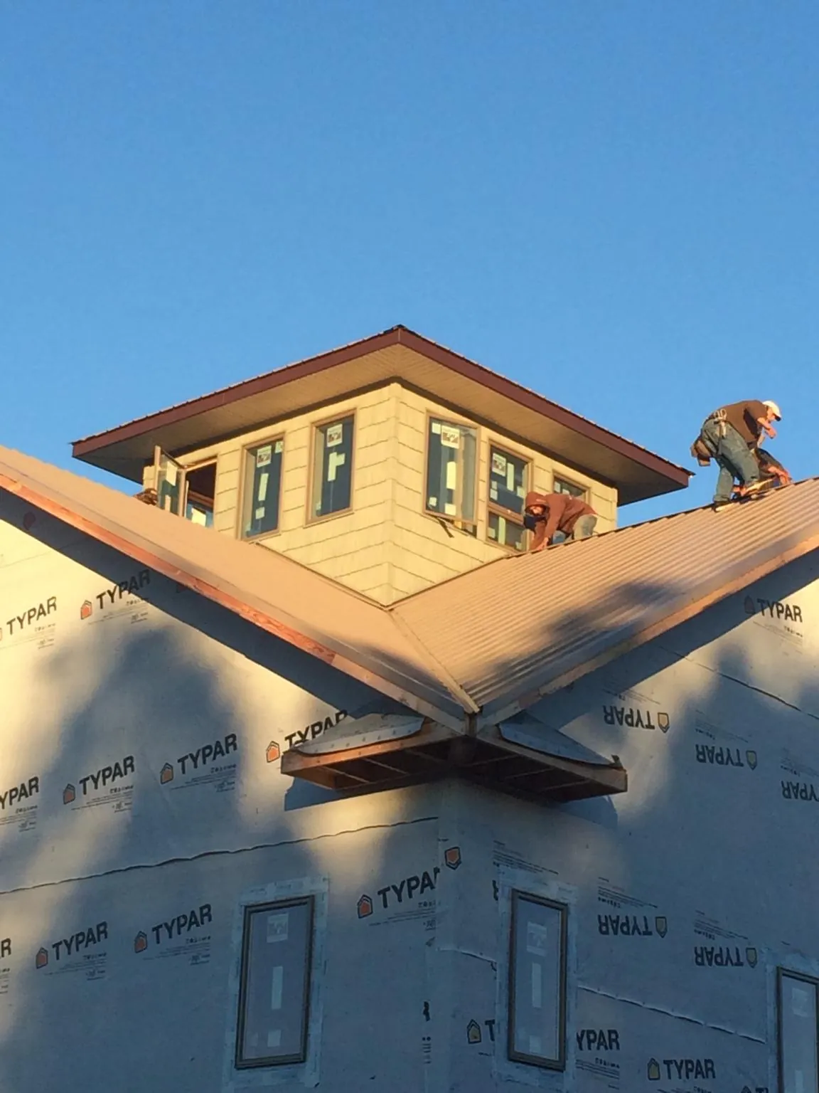 Roofers working around a rooftop cupola on a new metal roof at sunset — Roof Waterproofing in Montana Mines by Roofing Brothers